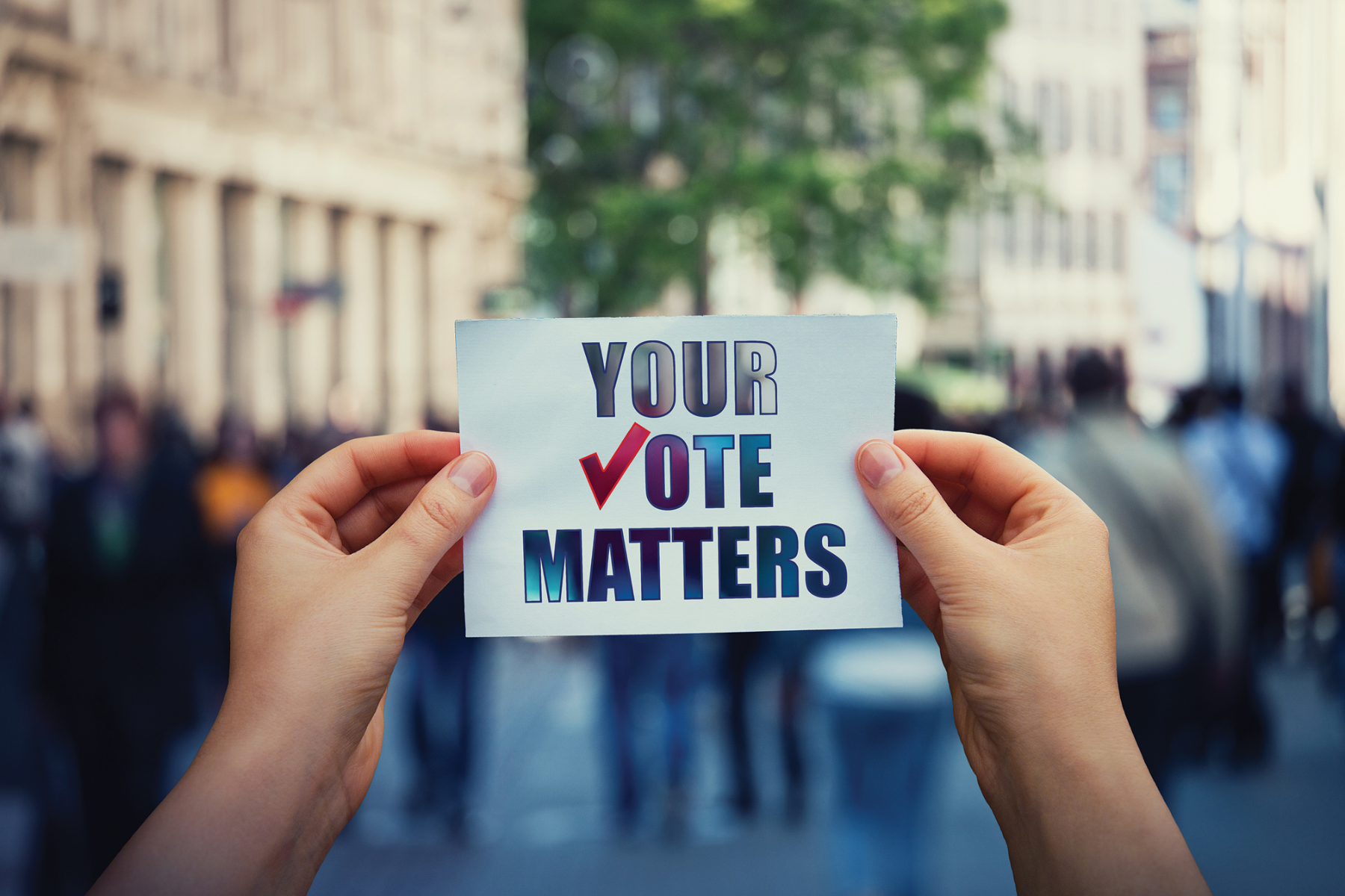 Both hands are holding a piece of paper with the words "your vote matters" written on it