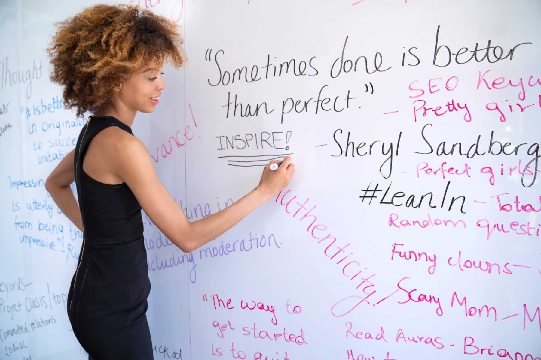 A young woman uses a white board to write